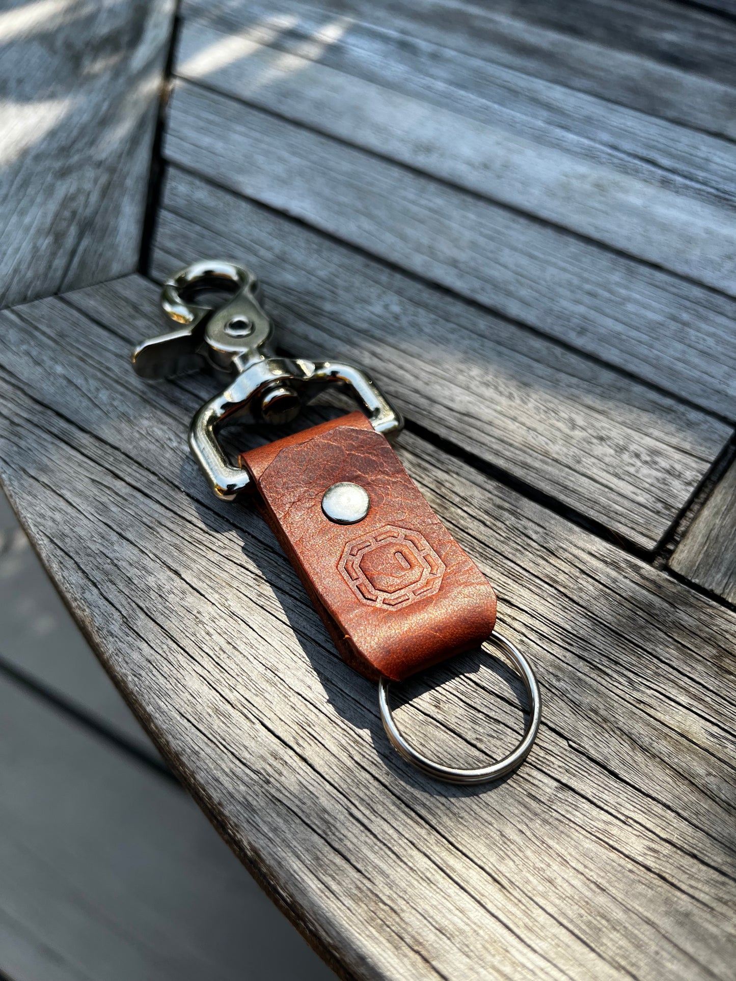 Brown leather keychain with metal clip on a wooden surface