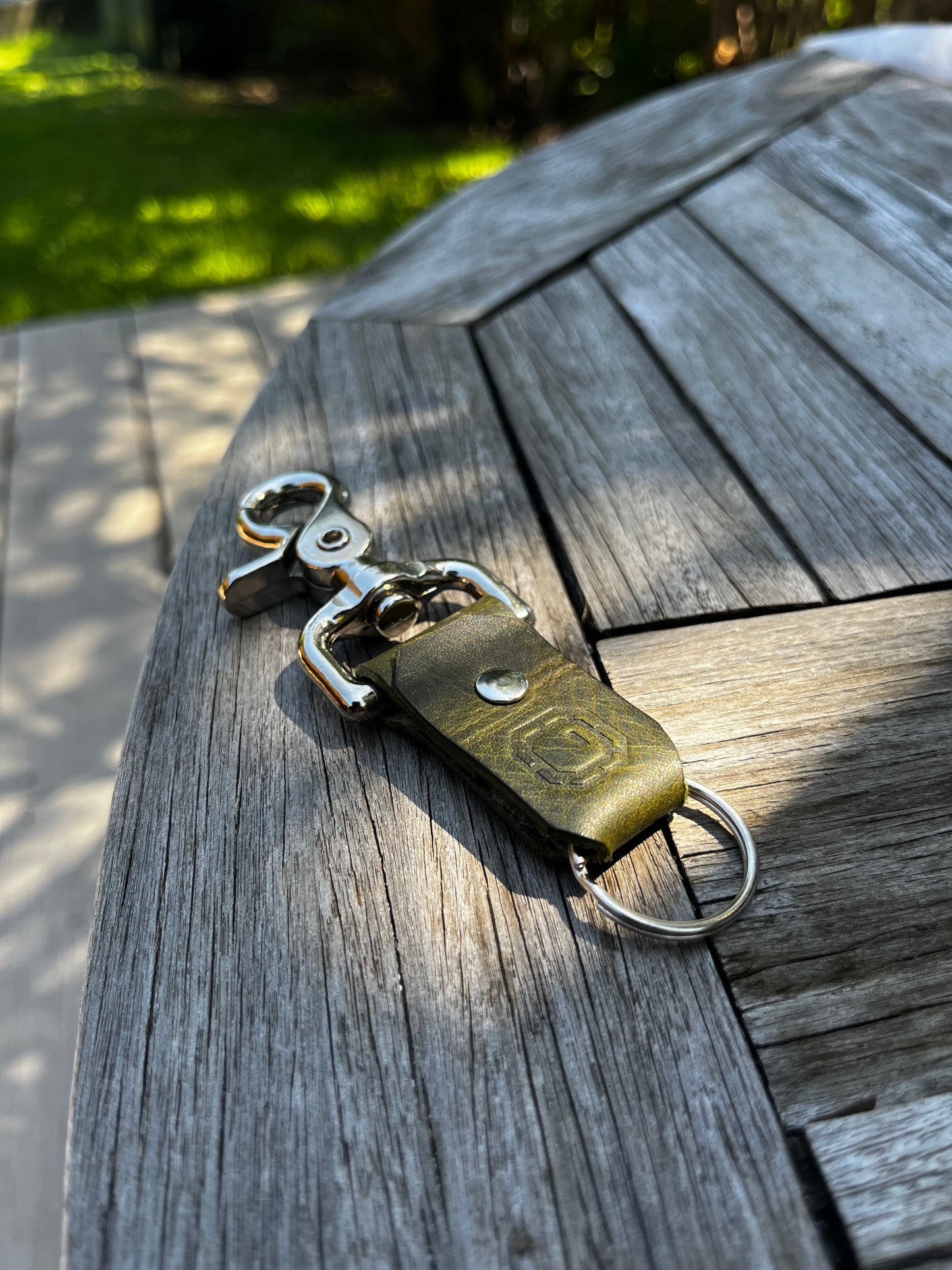 Olive green leather key fob on a wooden surface