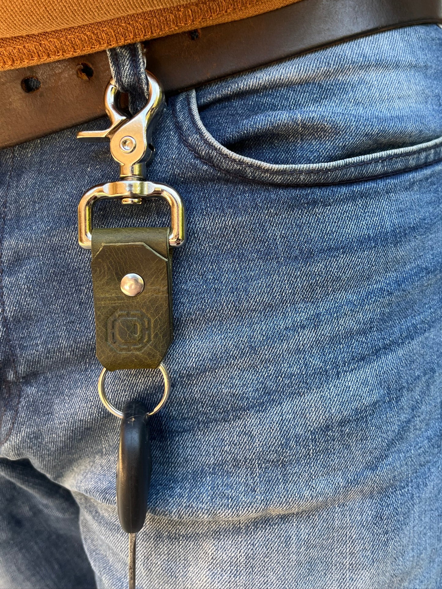 Close-up of a leather strap with a metal buckle on blue jeans.