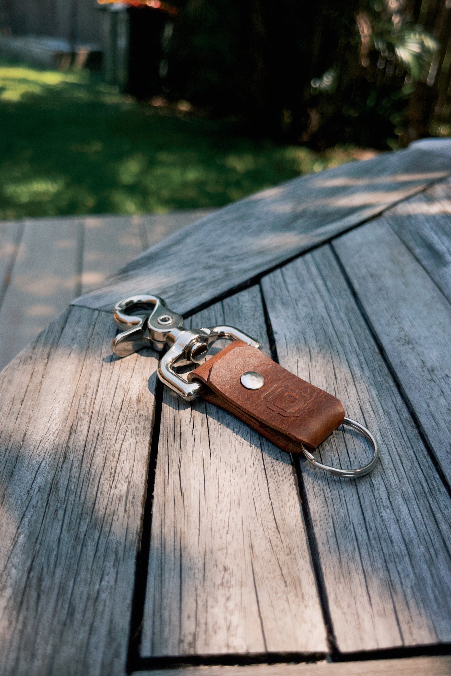 Keychain with brown leather tag on a wooden surface outdoors