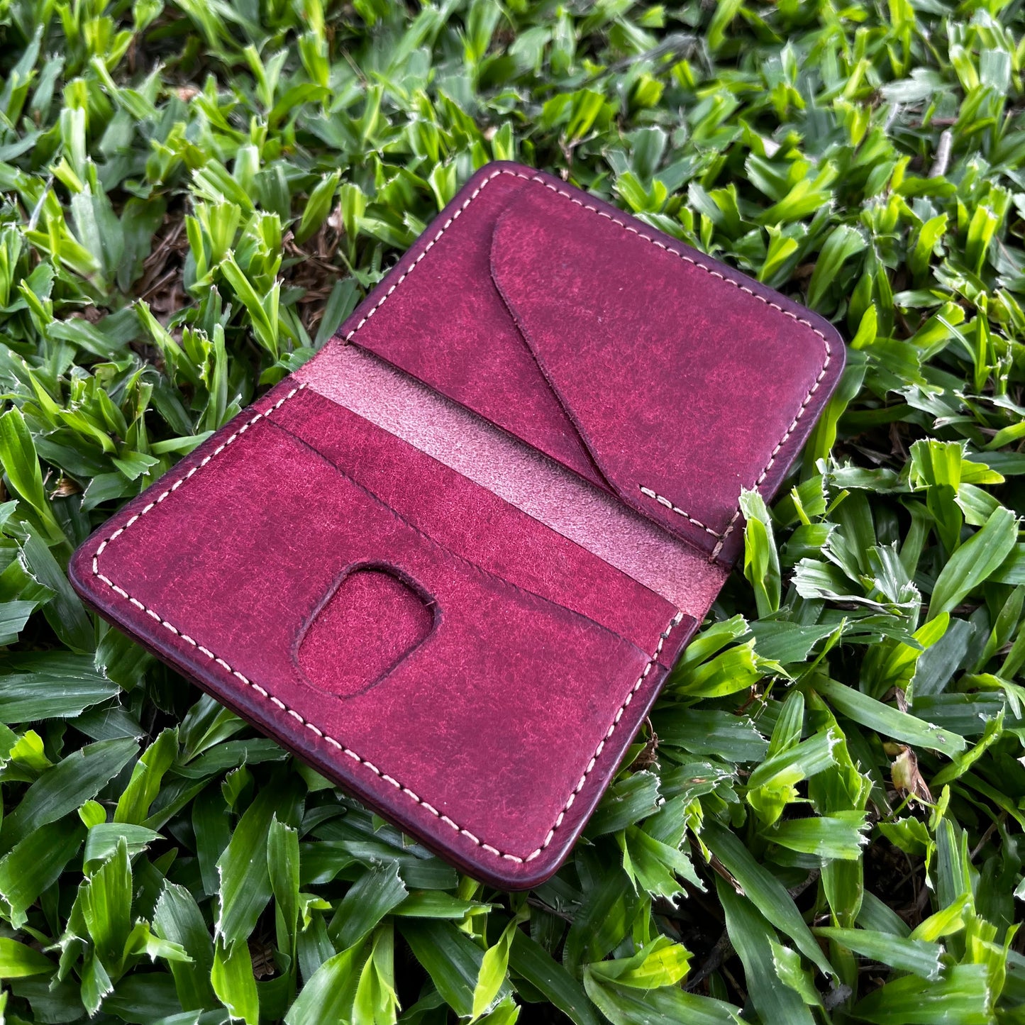 Burgundy leather wallet on green grass