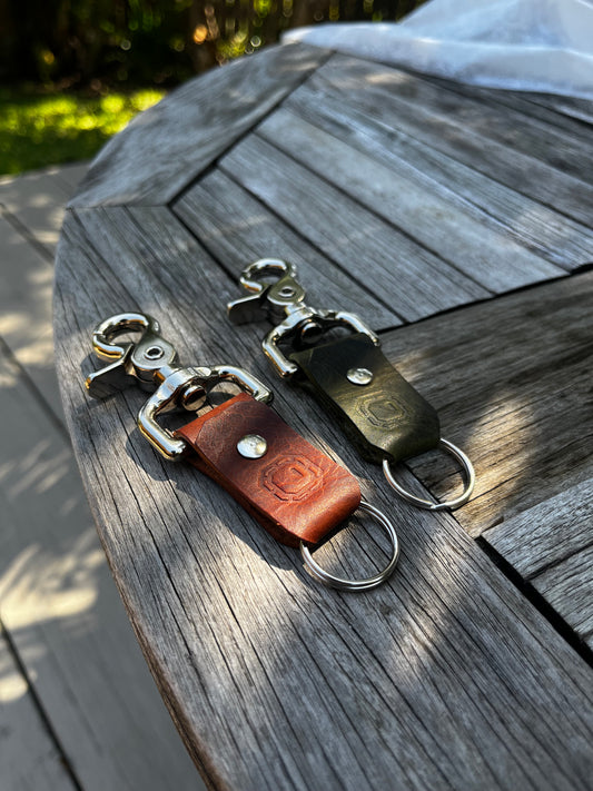 Two leather keychains on a wooden surface
