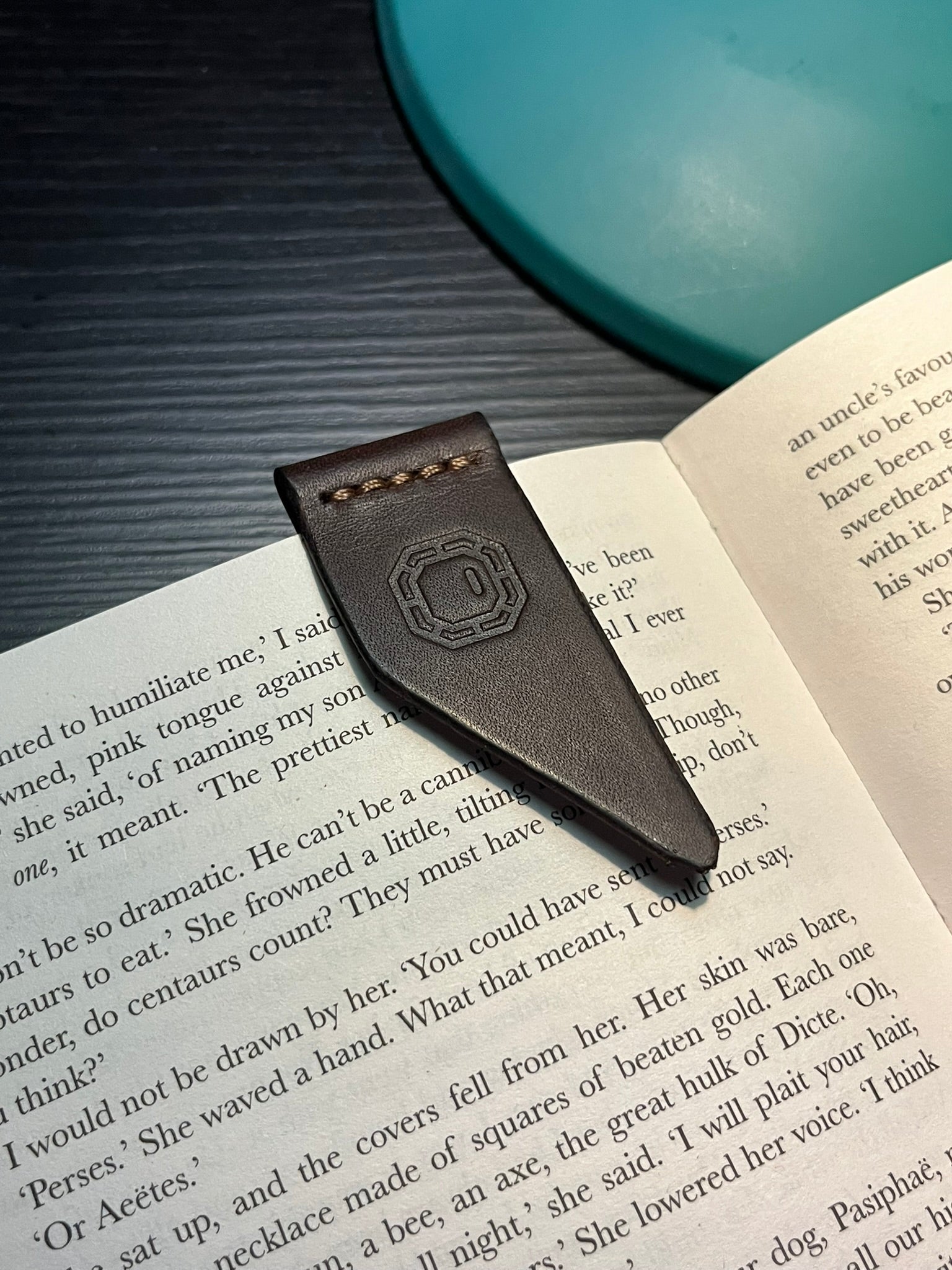 Leather bookmark with a brand logo on an open book