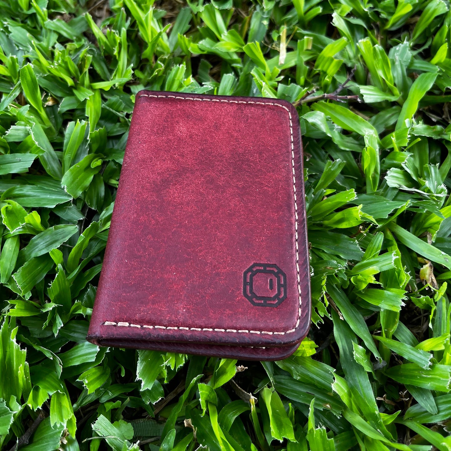 Red leather wallet on green grass
