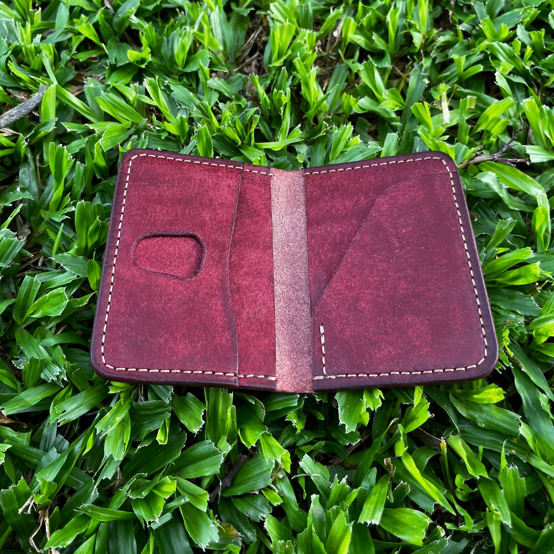Red leather wallet on green grass