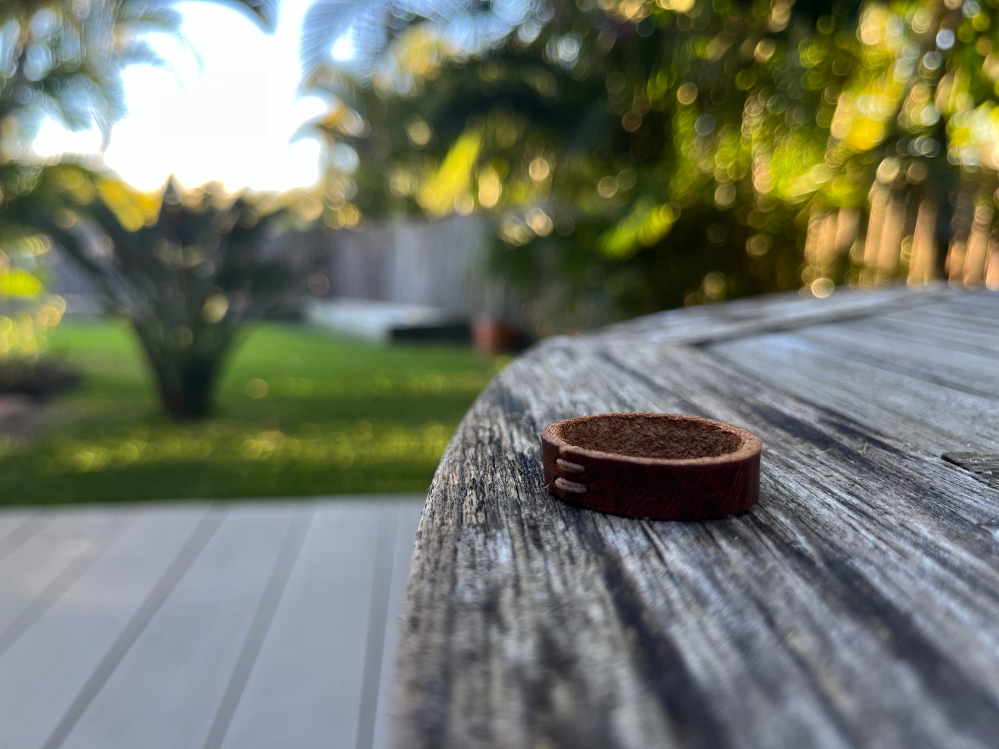 Close-up of a waxy cognac leather ring with a blurred outdoor background
