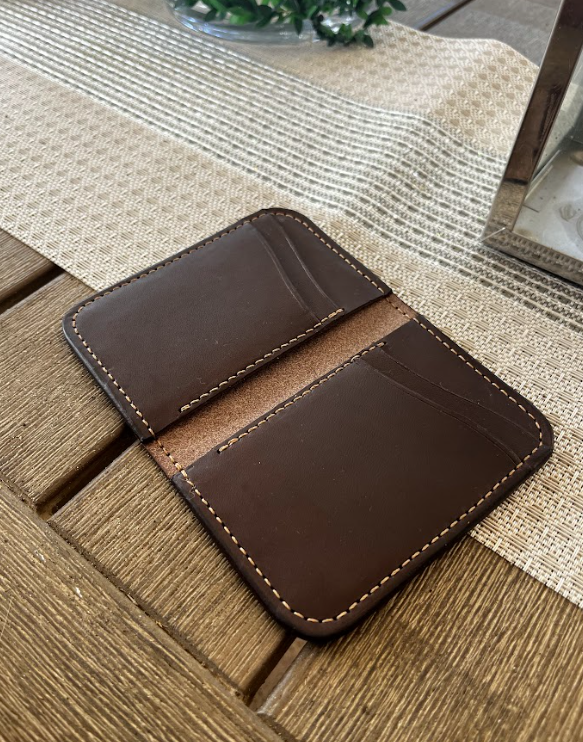 Brown leather wallet on a wooden surface with a neutral background